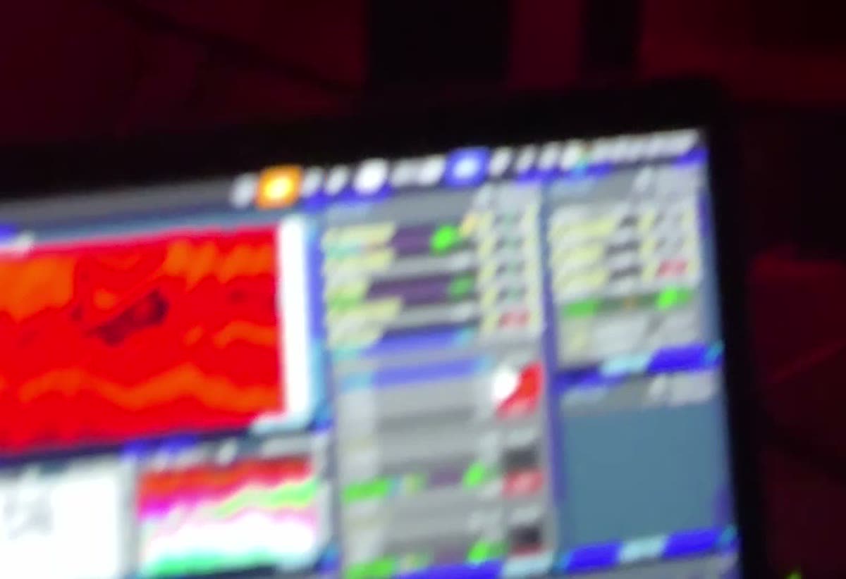 Vista desde la cabina de Feca: la laptop con la previa y la grilla de clips, y la pista iluminada de rojo al fondo